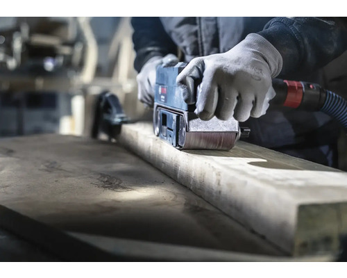 Artisan ponçant du bois avec une ponceuse à bande