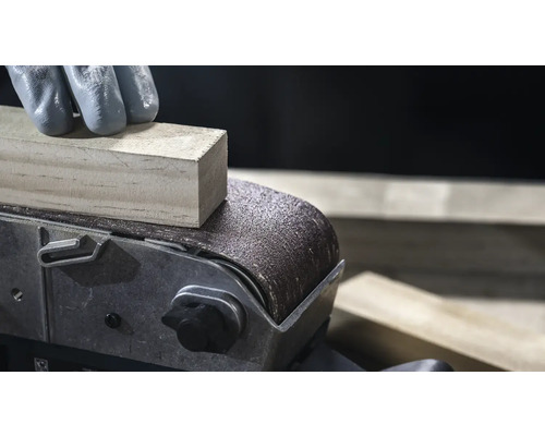 Gros plan d'une ponceuse à bande qui lisse une pièce de bois