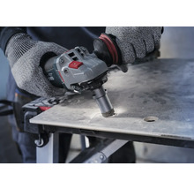 Bediener bohrt mit einem Winkelschleifer ein Loch in eine Fliese.