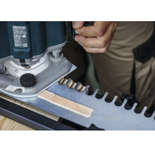 Une défonceuse en train de travailler une pièce à l'aide d'un gabarit pour les assemblages à queues d'aronde.