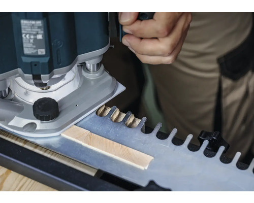 Une défonceuse en train de travailler une pièce à l'aide d'un gabarit pour les assemblages à queues d'aronde.