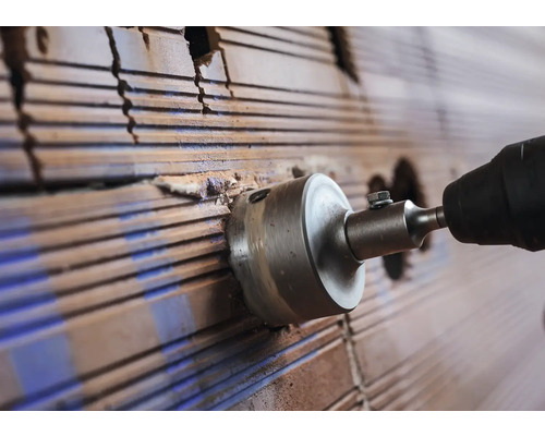 Lochsäge bohrt ein Loch in eine Ziegelwand