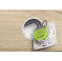 Contrôleur de gradation intelligent Shelly Dimmer Gen4 lors de l'installation dans une boîte d'encastrement avec câblage et support d'interrupteur.