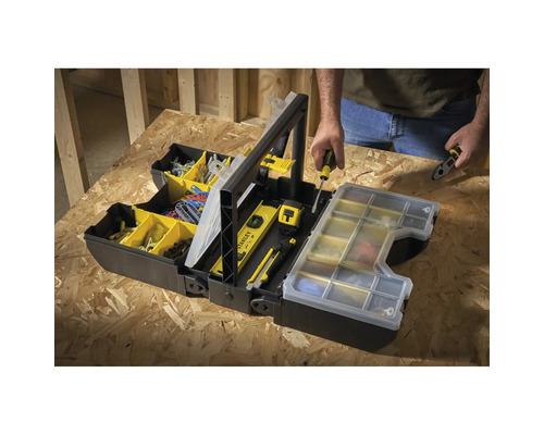 Offene schwarze Werkzeugkiste mit Werkzeugen und Zubehör, im Hintergrund eine Person.