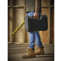 Eine Person trägt einen Werkzeugkasten und eine Wasserwaage von Stanley.