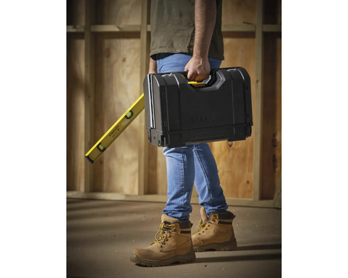 Eine Person trägt einen Werkzeugkasten und eine Wasserwaage von Stanley.
