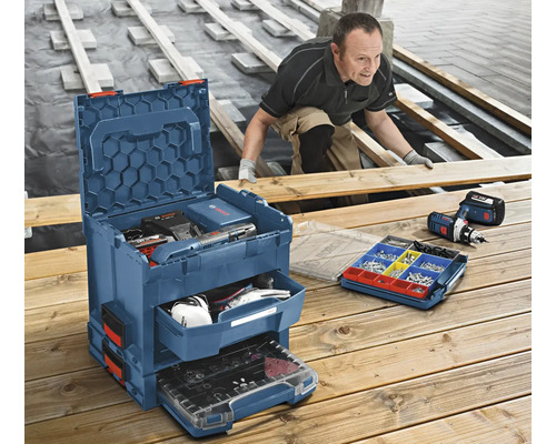 Boîte à outils bleue avec outils, vis et un ouvrier travaillant le bois