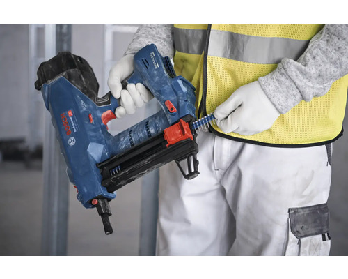 Une personne remplit un cloueur bleu avec des clous.