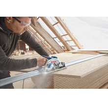 Un artisan coupe des panneaux de bois avec une scie circulaire sur un rail de guidage. Logo Bosch.