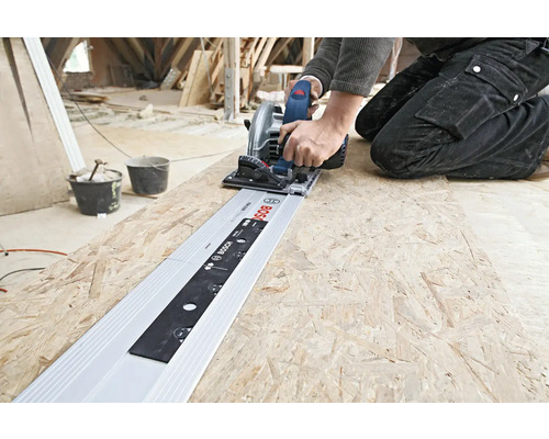 Artisan coupant une plaque de bois avec une scie circulaire et un rail de guidage de Bosch