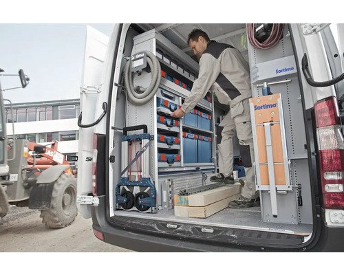 Un artisan range des outils dans un système d'étagères Sortimo dans une camionnette pour l'organisation et l'efficacité.