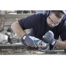 Un homme meule du métal avec une meuleuse d'angle, des étincelles jaillissent