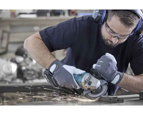 Un homme meule du métal avec une meuleuse d'angle, des étincelles jaillissent