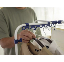 Une personne accroche des vêtements sur un étendoir.