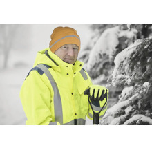 Homme avec veste jaune, bonnet et gants dans la neige avec râteau à feuilles