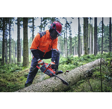 Un forestier coupe une bûche avec une tronçonneuse dans la forêt.