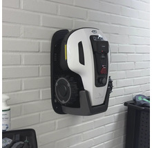 Robot tondeuse mural sur un mur de briques