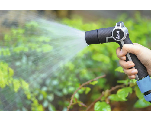 Une main tient un pistolet d'arrosage et arrose des plantes.