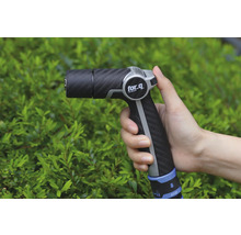 Lance d'arrosage dans la main devant des buissons