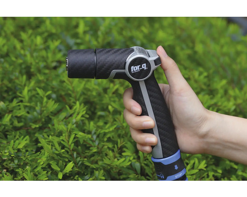 Lance d'arrosage dans la main devant des buissons