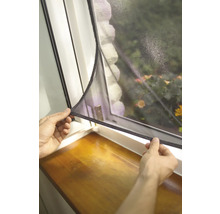 Une personne fixe une moustiquaire à une fenêtre.