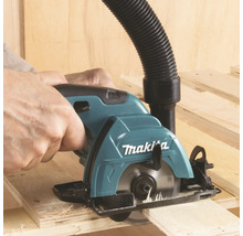 Scie circulaire portative Makita coupant du bois avec un tuyau pour aspirateur raccordé.
