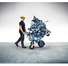 Homme avec casque de protection poussant une brouette à batterie Makita chargée de nombreux outils électroportatifs Makita.