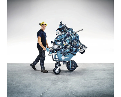 Homme avec casque de protection poussant une brouette à batterie Makita chargée de nombreux outils électroportatifs Makita.