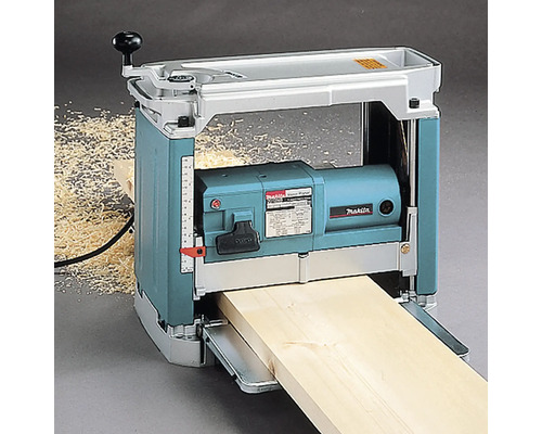 Makita Dickenhobel hobelt ein Holzbrett, mit sichtbaren Holzspänen daneben.