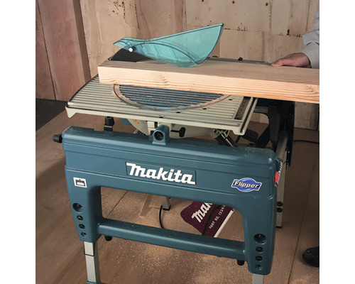 Scie à onglet et sur table de chantier Makita Flipper en train de couper une planche de bois.