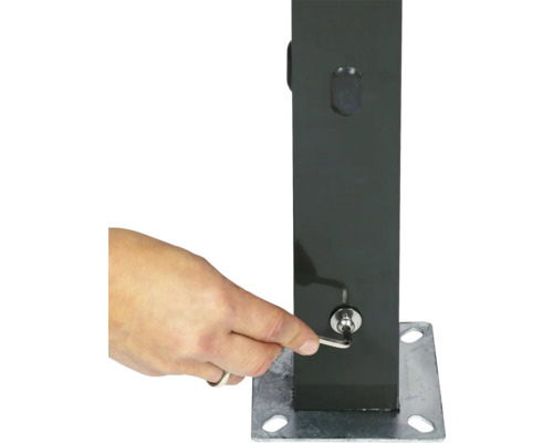 Eine Hand zieht mit einem Innensechskantschlüssel eine Schraube an einem anthrazitfarbenen Metallpfosten mit silberner Bodenplatte fest.