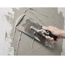 Maçon enduisant un mur avec une taloche