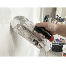 Taloche à lisser Superglatt avec manche dans la main lors du plâtrage d'un mur