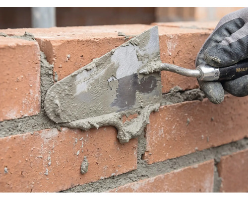 Maurer beim Verfugen einer Ziegelwand mit einer Maurerkelle