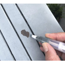 Réparation des dommages de peinture sur une surface en bois avec un stylo de retouche