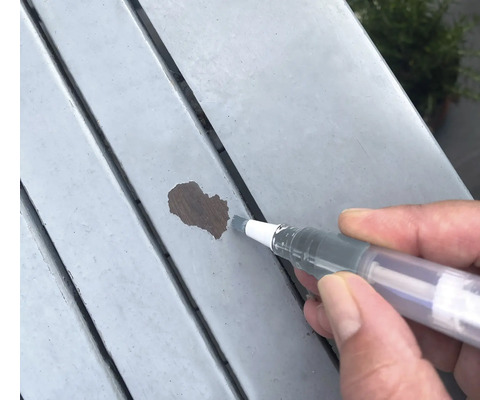 Réparation des dommages de peinture sur une surface en bois avec un stylo de retouche