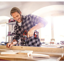 Ein Mann bohrt mit einem Akku-Bohrschrauber ein Holzbrett.