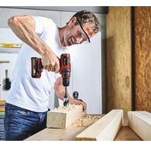 Un homme perce un trou dans une pièce de bois avec une perceuse-visseuse sans fil