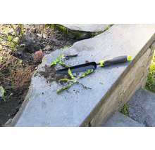 Outil de jardin et mauvaises herbes sur des marches en pierre
