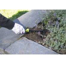 Une personne utilise une griffe de jardin pour ameublir la terre dans un potager surélevé.