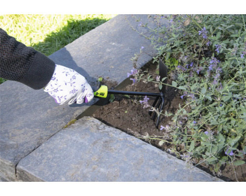 Une personne utilise une griffe de jardin pour ameublir la terre dans un potager surélevé.