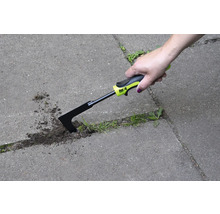 Une main utilise un couteau à joints pour enlever les mauvaises herbes entre les pavés.