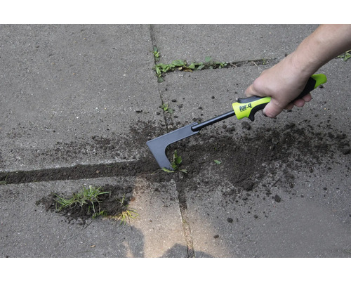 Une personne enlève les mauvaises herbes avec un désherbeur de joints sur une surface pavée.