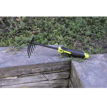 Râteau à feuilles et de jardin avec dents et manche en plastique sur mur de pierre