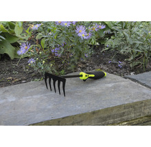 Râteau de jardin à cinq dents devant un parterre de fleurs