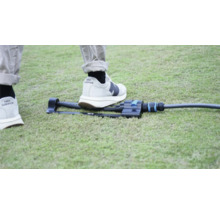 Arroseur de jardin sur pelouse avec un pied pour comparer la taille.