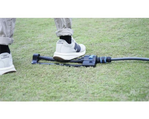 Arroseur de jardin sur pelouse avec un pied pour comparer la taille.