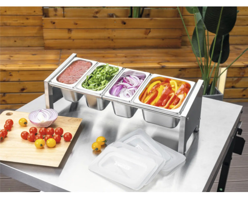 Tenneker Prep Station aus Edelstahl mit vier Gastronormbehältern auf einem Metalltisch, befüllt mit Saucen und geschnittenem Gemüse zum Grillen.
