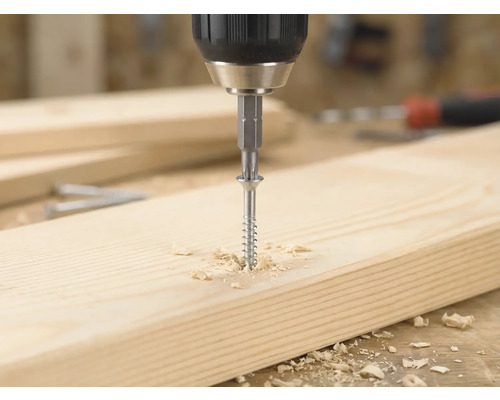 Akkuschrauber dreht eine Holzschraube mit einem Bit in ein helles Holzbrett, umgeben von Holzspänen.