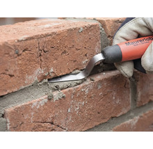 Un fer à jointoyer Maurerlob est utilisé pour presser le mortier dans le joint entre deux briques rouges.
